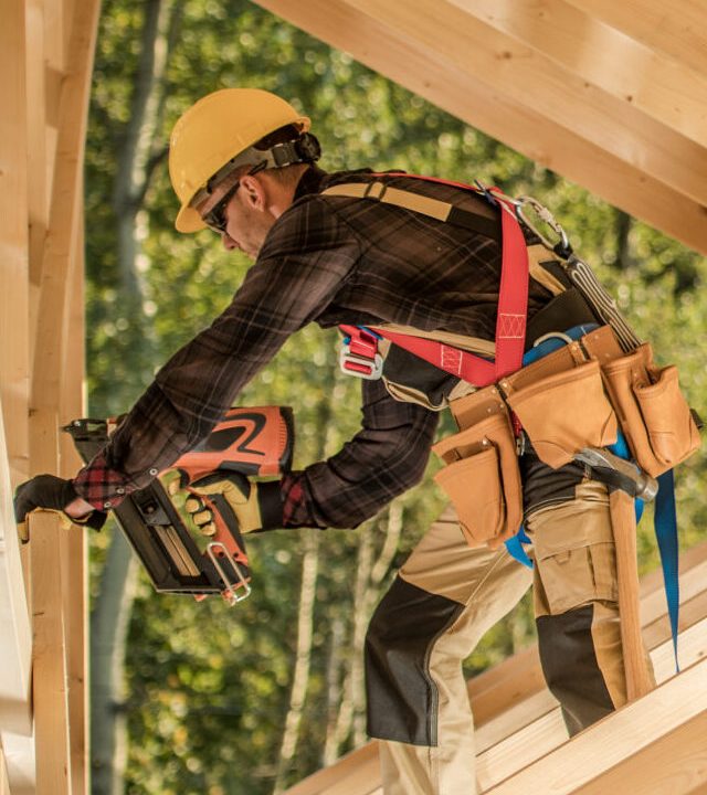 construction worker builds wooden framework of modern house in daylight